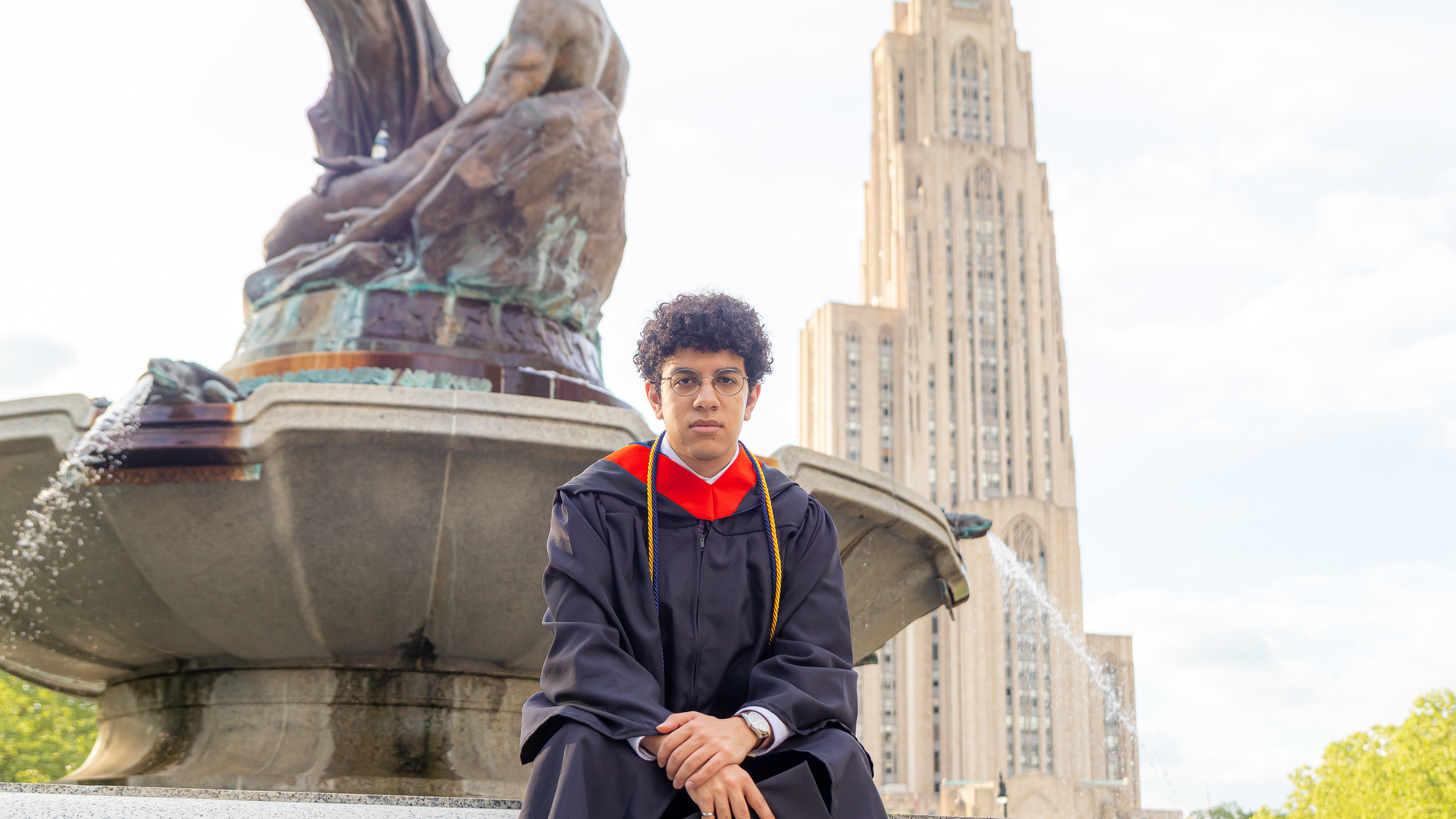 a graduation photo with a fountain and cathedral in the background